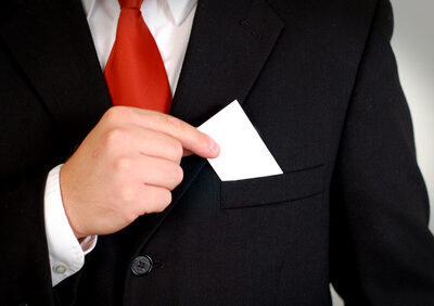 A businessman in a suit holds a blank white business card that is ready for your logo!